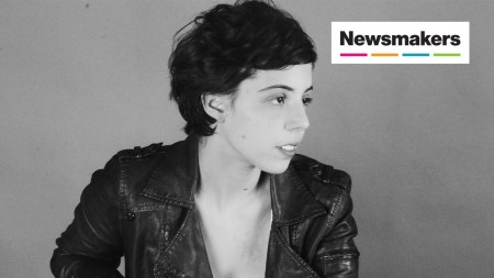 A black and white photo of a woman in a leather jacket and short hair.